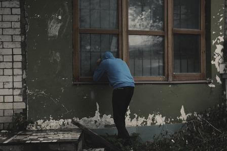 A man is looking into someone's house through a window
